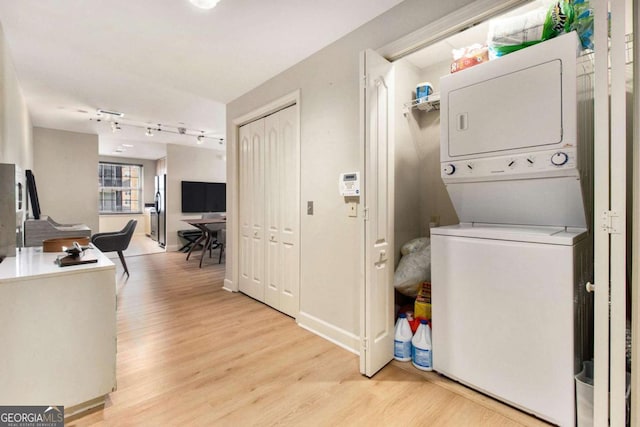 washroom with light hardwood / wood-style floors and stacked washing maching and dryer