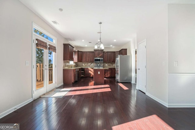 kitchen featuring hanging light fixtures, stainless steel appliances, tasteful backsplash, dark hardwood / wood-style flooring, and a kitchen island