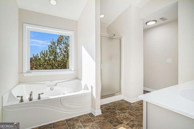 bathroom featuring vanity, independent shower and bath, and vaulted ceiling