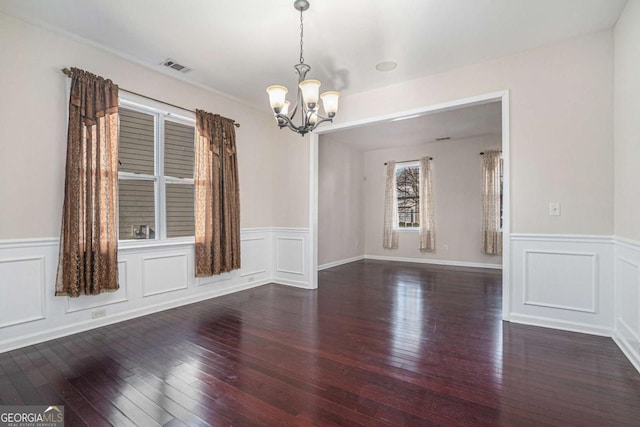 unfurnished room featuring dark hardwood / wood-style floors and an inviting chandelier