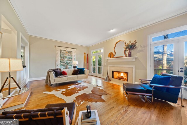 living room featuring a premium fireplace, french doors, ornamental molding, and hardwood / wood-style flooring