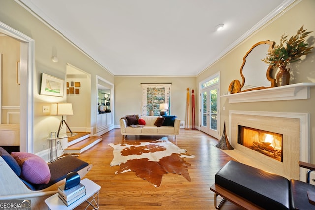 living room with light wood-type flooring, crown molding, a high end fireplace, and french doors