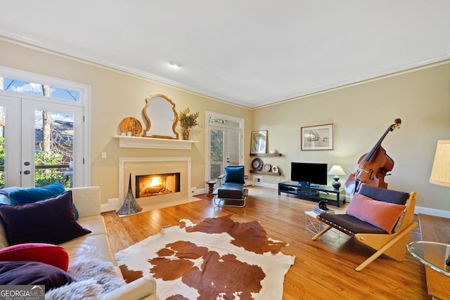 living room with crown molding, french doors, and light wood-type flooring