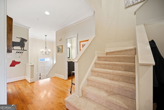 staircase with hardwood / wood-style flooring, an inviting chandelier, and crown molding