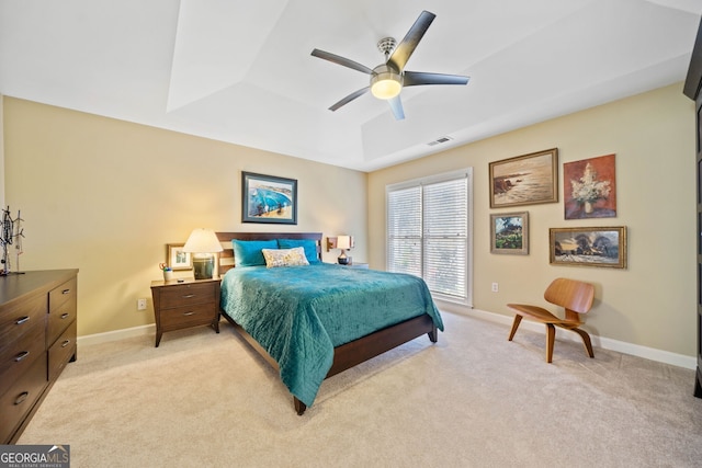 bedroom featuring a raised ceiling, ceiling fan, and light colored carpet