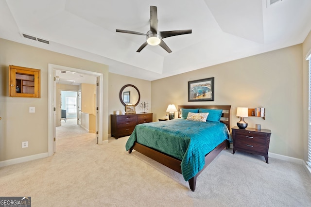 bedroom featuring light colored carpet, a raised ceiling, and ceiling fan