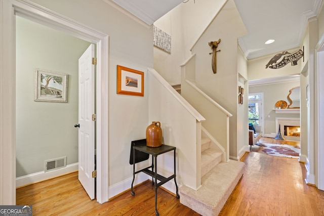 stairs featuring crown molding and hardwood / wood-style flooring