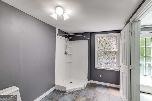 bathroom with tile patterned floors, toilet, and a shower