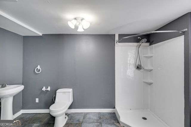 bathroom featuring a shower, toilet, and sink