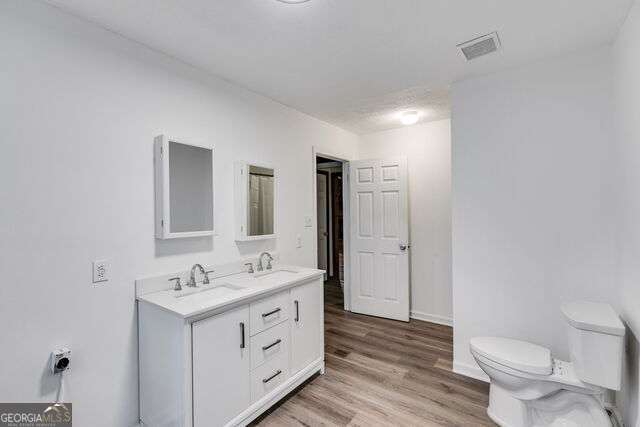 bathroom with toilet, vanity, and hardwood / wood-style flooring