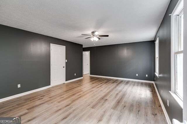 unfurnished room with ceiling fan, a textured ceiling, and light hardwood / wood-style flooring