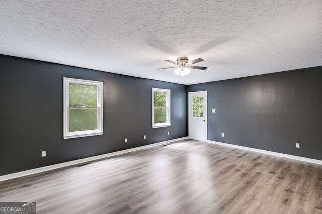 empty room featuring ceiling fan, wood-type flooring, and a textured ceiling