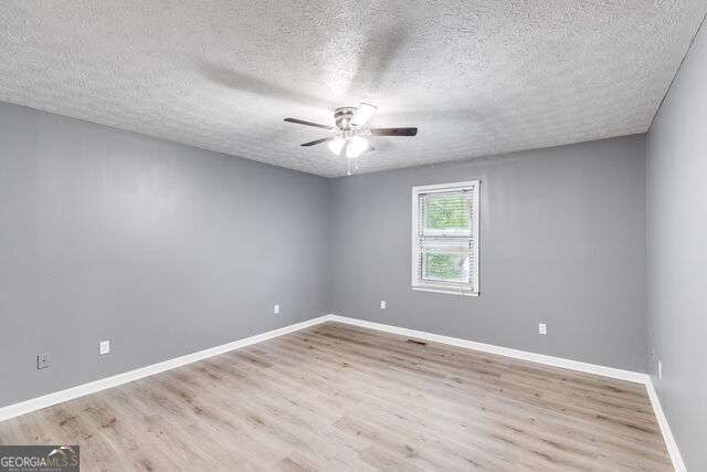 spare room with a textured ceiling and light wood-type flooring