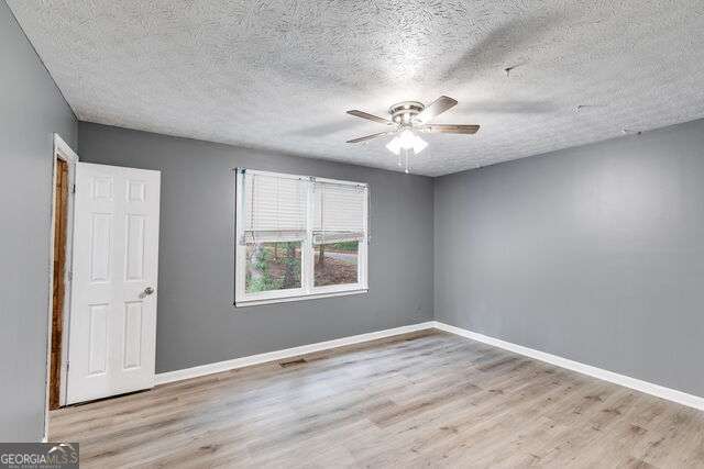 empty room with ceiling fan, a textured ceiling, and light hardwood / wood-style flooring