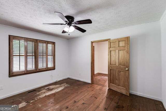 spare room with ceiling fan, dark hardwood / wood-style flooring, and a textured ceiling