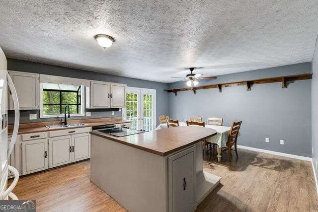 kitchen featuring black electric stovetop, a kitchen island, ceiling fan, light hardwood / wood-style floors, and white cabinetry