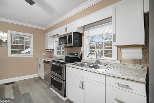 kitchen with sink, light wood-type flooring, ornamental molding, white cabinetry, and stainless steel appliances