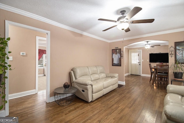 living room with ceiling fan, dark wood-type flooring, a textured ceiling, and ornamental molding