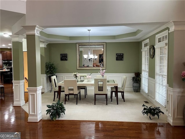 dining room featuring a raised ceiling, crown molding, hardwood / wood-style floors, and an inviting chandelier