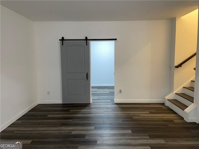 empty room featuring a barn door and dark hardwood / wood-style floors