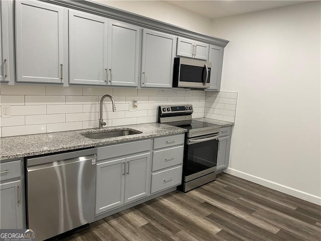 kitchen featuring dark wood-type flooring, sink, decorative backsplash, gray cabinets, and appliances with stainless steel finishes