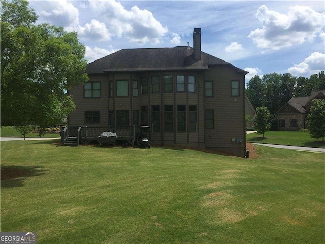 back of house featuring a wooden deck and a lawn