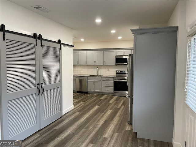 kitchen featuring gray cabinetry, sink, stainless steel appliances, dark wood-type flooring, and decorative backsplash