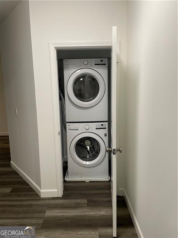 washroom featuring dark hardwood / wood-style flooring and stacked washing maching and dryer