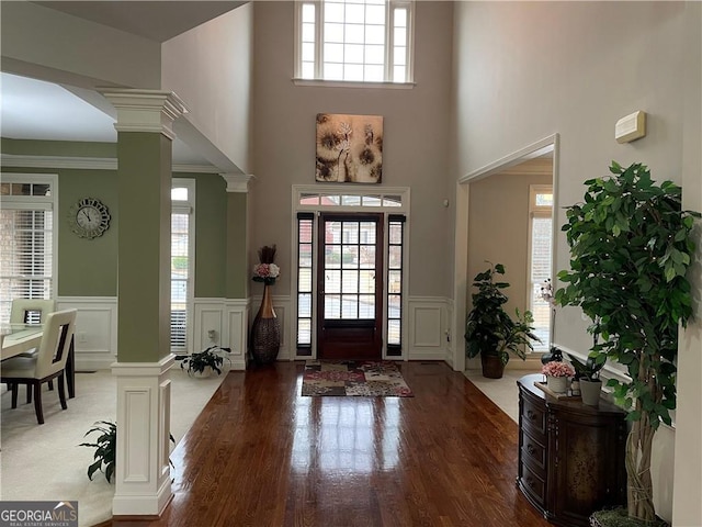 foyer entrance with a towering ceiling, ornate columns, and a healthy amount of sunlight