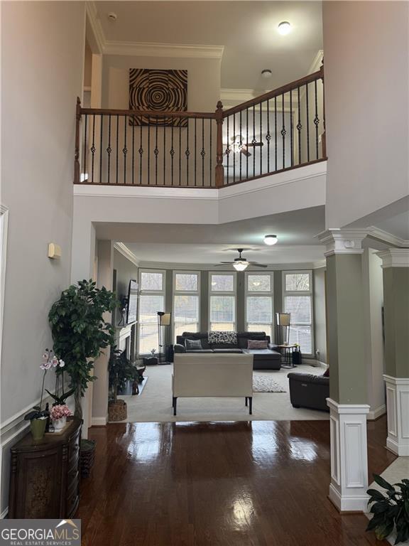 foyer featuring hardwood / wood-style floors, a high ceiling, crown molding, ceiling fan, and decorative columns