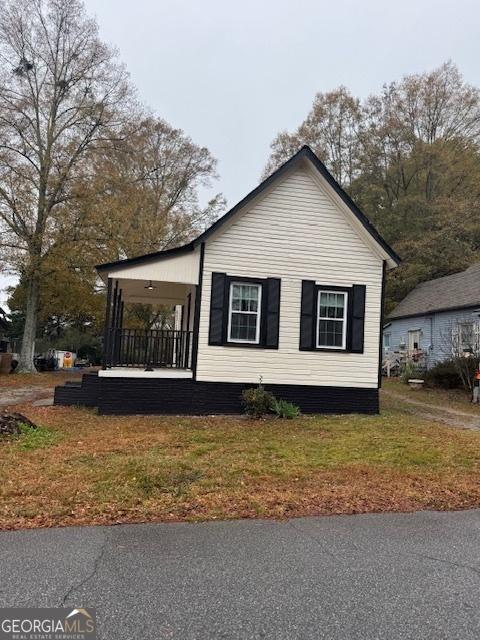 view of side of home featuring a lawn and covered porch