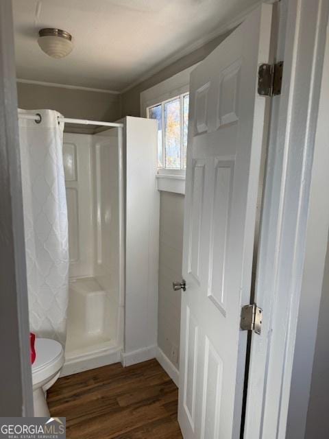 bathroom with a shower, wood-type flooring, and toilet