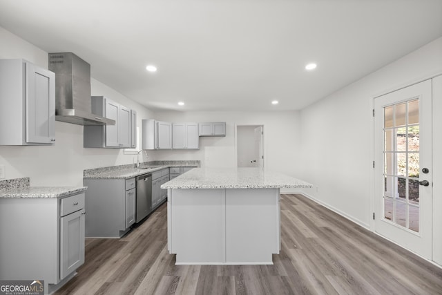 kitchen with light wood-type flooring, stainless steel dishwasher, wall chimney range hood, a center island, and gray cabinets