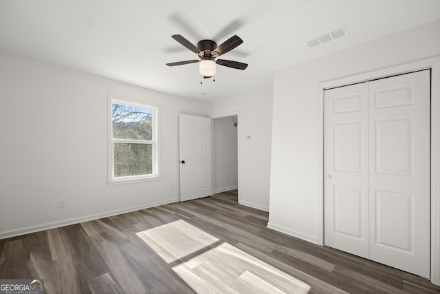 unfurnished bedroom featuring dark hardwood / wood-style flooring, a closet, and ceiling fan