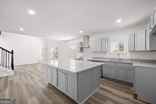 kitchen featuring gray cabinetry, sink, wall chimney range hood, and hardwood / wood-style flooring