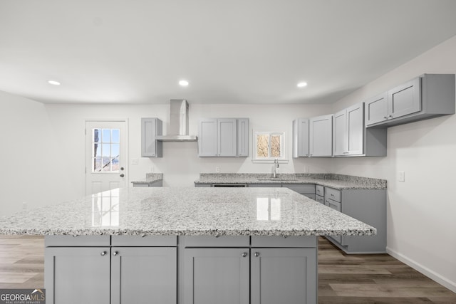 kitchen featuring gray cabinetry, wall chimney exhaust hood, and a kitchen island