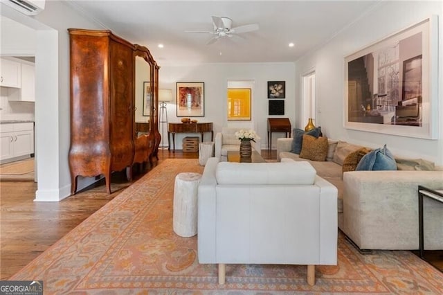 living room with hardwood / wood-style flooring, ceiling fan, crown molding, and a wall mounted AC