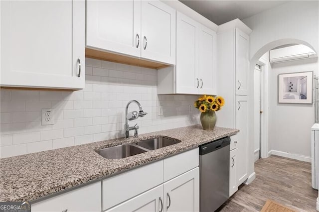 kitchen featuring dishwasher, sink, light stone counters, light hardwood / wood-style floors, and white cabinets