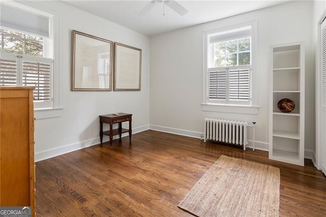 empty room with a healthy amount of sunlight, dark hardwood / wood-style flooring, and radiator