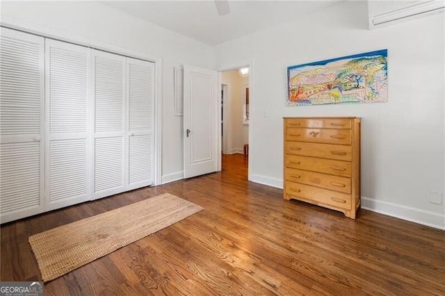 unfurnished bedroom featuring a wall mounted air conditioner, a closet, ceiling fan, and dark wood-type flooring