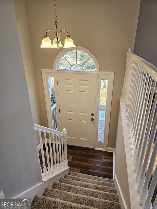 entrance foyer with dark hardwood / wood-style floors and an inviting chandelier