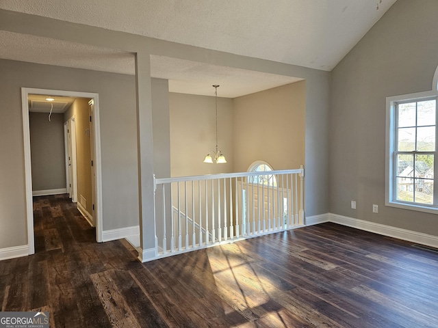 unfurnished room with lofted ceiling, a textured ceiling, and dark wood-type flooring