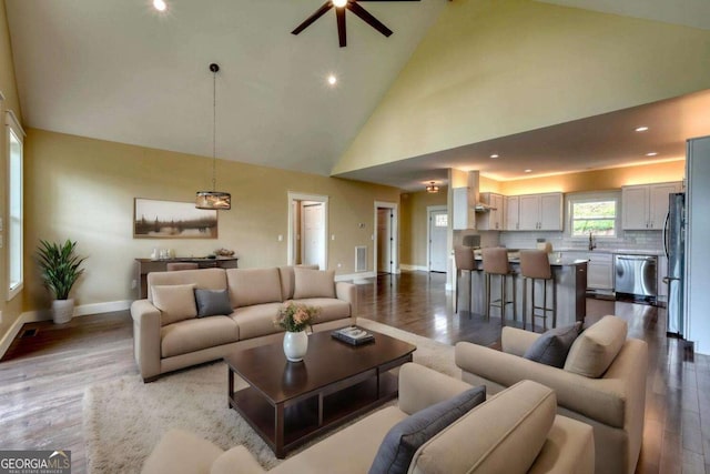 living room featuring light wood-type flooring, high vaulted ceiling, ceiling fan, and sink