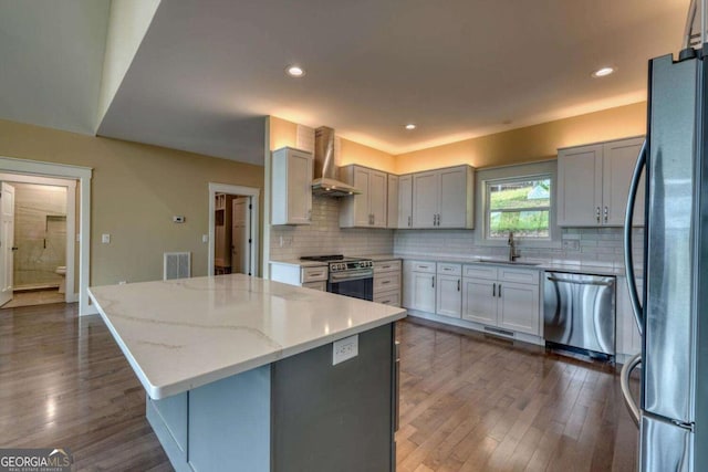 kitchen featuring light stone countertops, decorative backsplash, dark hardwood / wood-style flooring, wall chimney exhaust hood, and stainless steel appliances