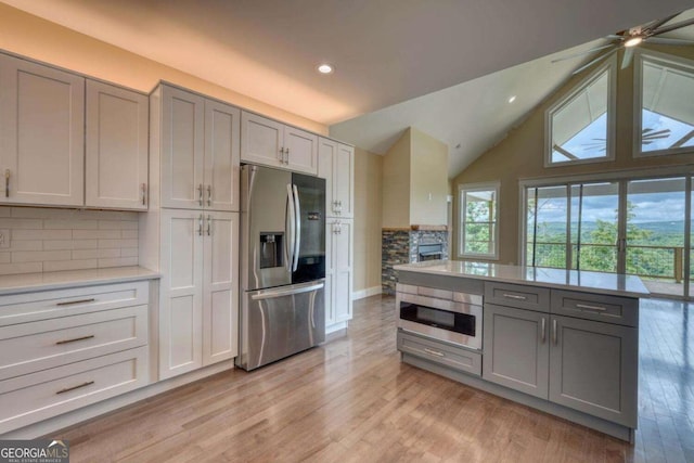 kitchen with appliances with stainless steel finishes, gray cabinets, tasteful backsplash, and light hardwood / wood-style floors