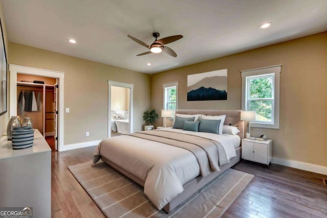 bedroom featuring wood-type flooring, a spacious closet, ensuite bath, and ceiling fan