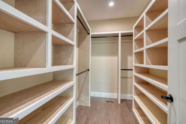 walk in closet with hardwood / wood-style flooring