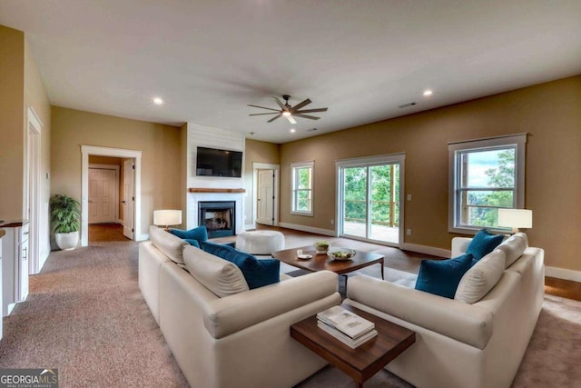 living room with light carpet, a fireplace, and ceiling fan