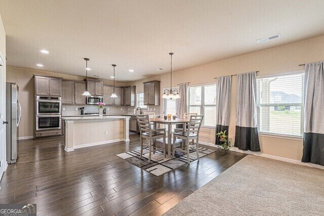 dining space with dark hardwood / wood-style flooring, sink, and an inviting chandelier