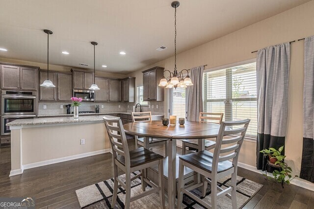 dining space featuring a chandelier, sink, and dark wood-type flooring